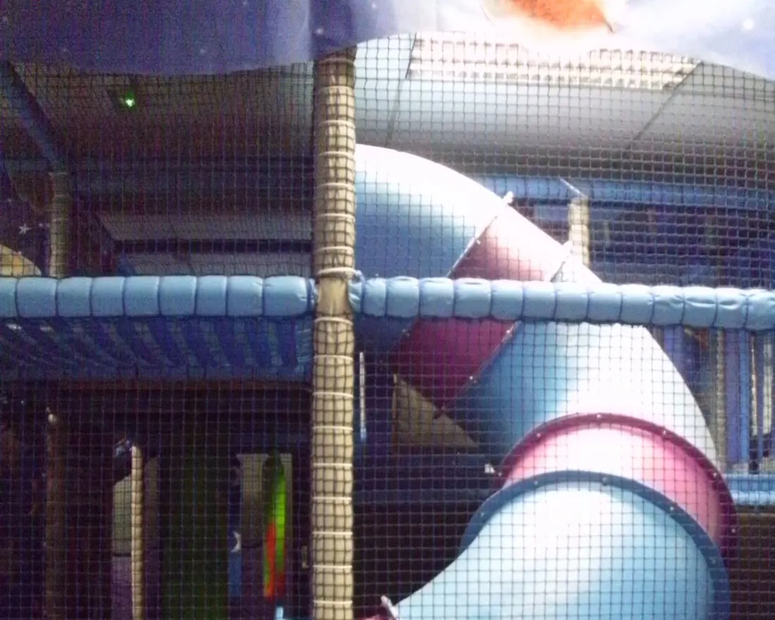 Tube slide and netted climbing frame in the Purple Planet soft play